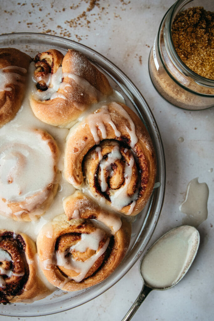 tray of quick cinnamon rolls swirled with icing next to a spoon