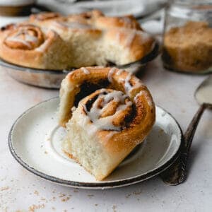 side view of quick cinnamon roll on a white plate with more in the background