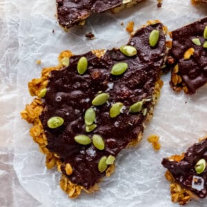 close up overhead shot of oat granola bar with a dark chocolate coating and pumpkin seeds on top