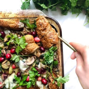 tray of stuffing on a white background with a gold spoon in hand