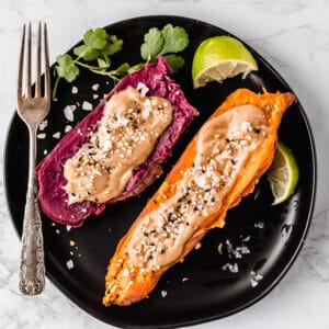 black plate with two instant pot purple sweet potatoes next to a fork