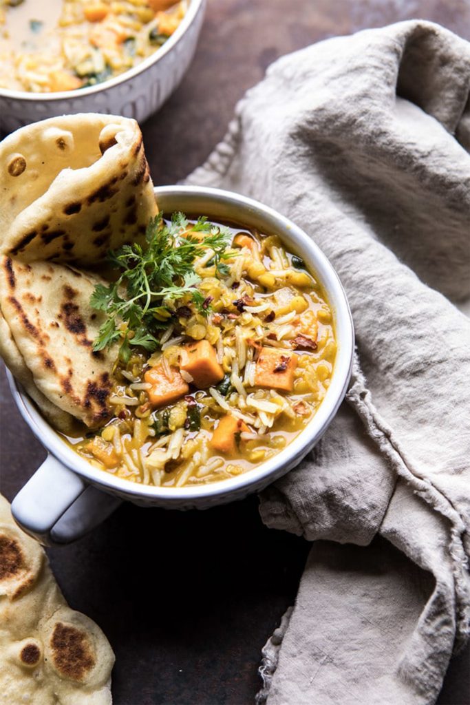white bowl of yellow lentil soup with naan bread