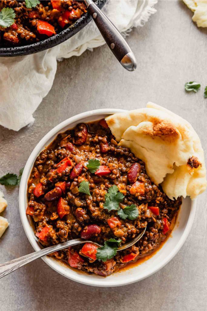 white bowl of red chili with bread