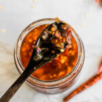 wooden spoon dipped into a jar of chile crisp