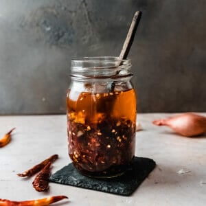 jar of homemade chili crisp with a wooden spoon sticking out