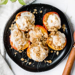 black circular plate with six grilled peaches with ice cream