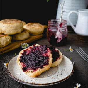 sliced open english muffin spread with blackberry jam