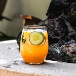 one cantaloupe cocktail next to a fire pit
