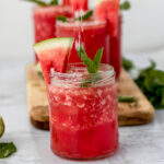 salted watermelon margaritas on a marble board with mint sprigs