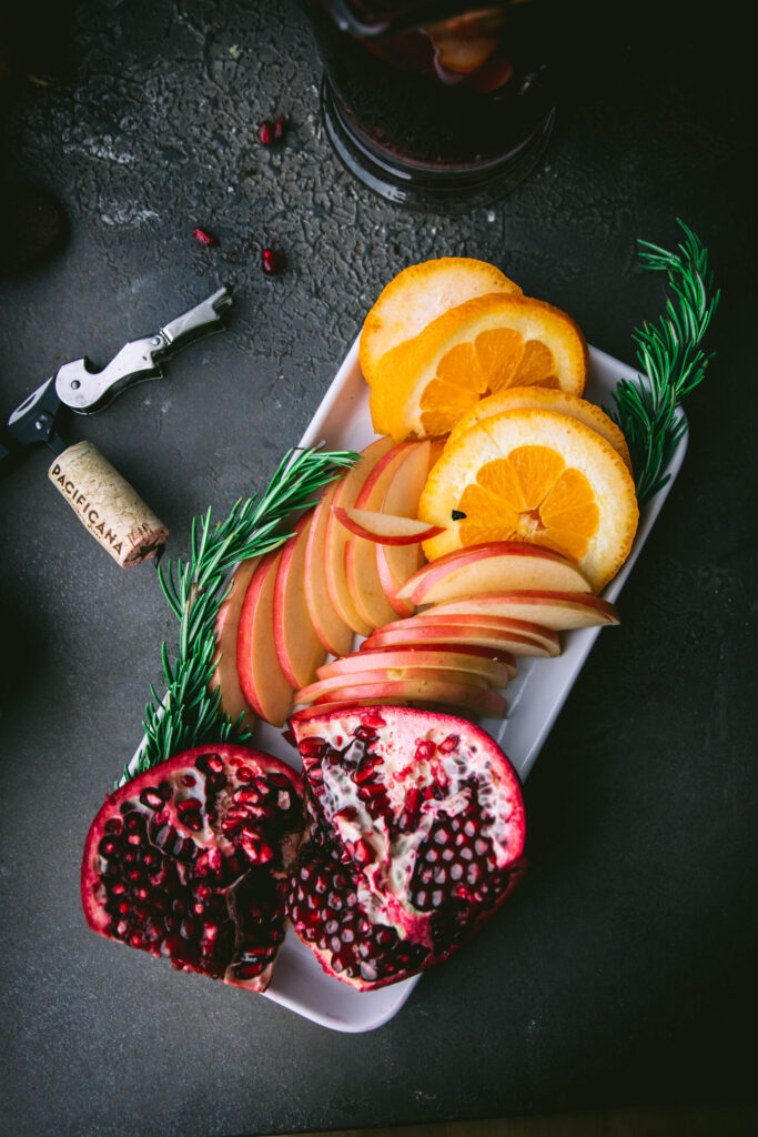 fruit board with pomegranate, orange, and apple slices