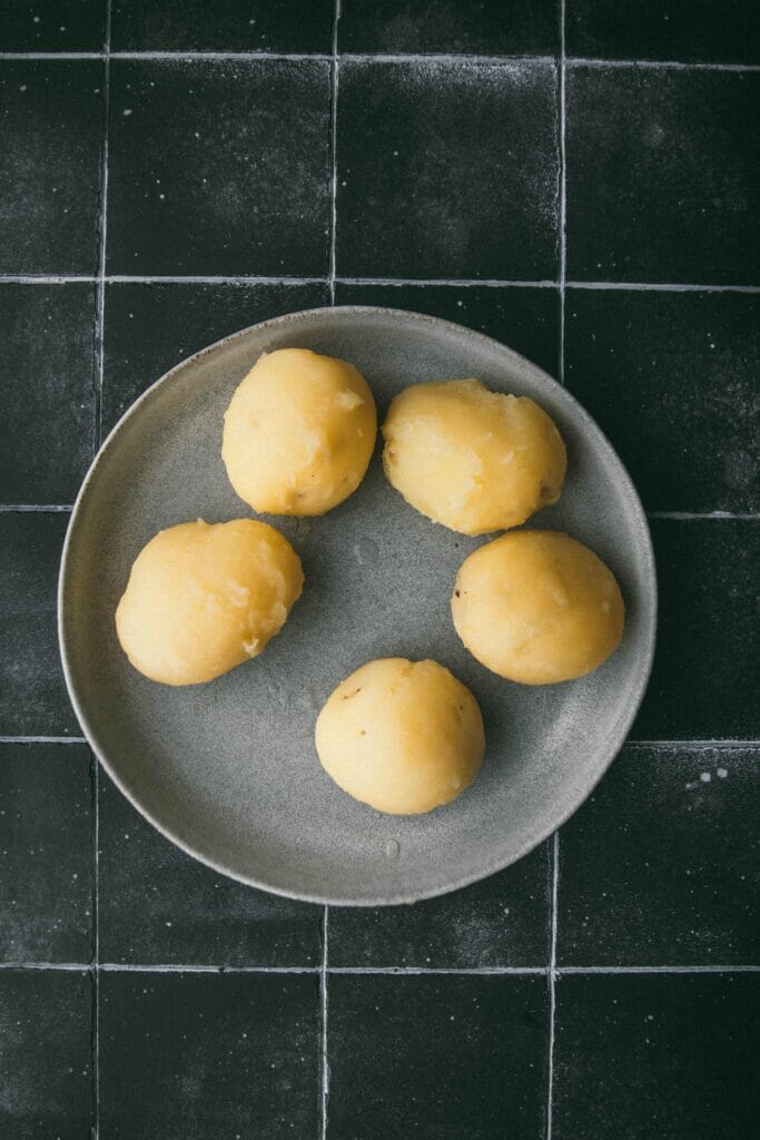 five skinned golden potatoes in a grey bowl