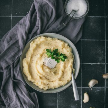 bowl of vegan mashed potatoes with a grey cloth on a black tile table