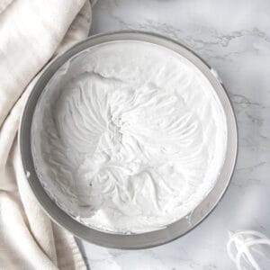 overhead shot of coconut whipped cream in a silver bowl next to a hand mixer