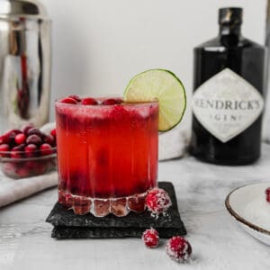 glass of cranberry gin fizz on a marble board in front of Hendricks gin