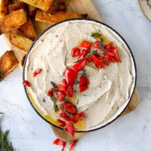 overhead shot of vegan white bean dip on a wooden board next to toasted bread