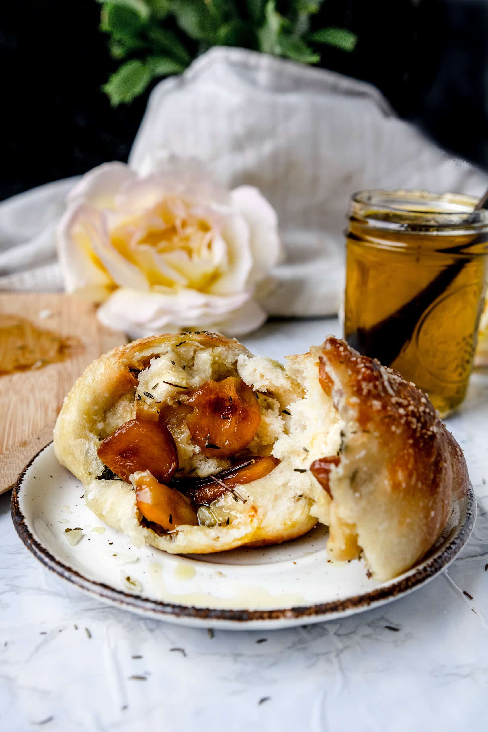 broken open garlic rolls on a white plate next to garlic olive oil in a jar