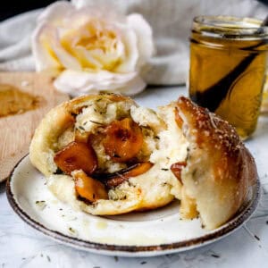 broken open garlic rolls on a white plate next to garlic olive oil in a jar