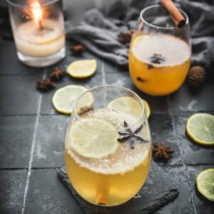 side view of two glasses of hot toddy cocktails next to a candle