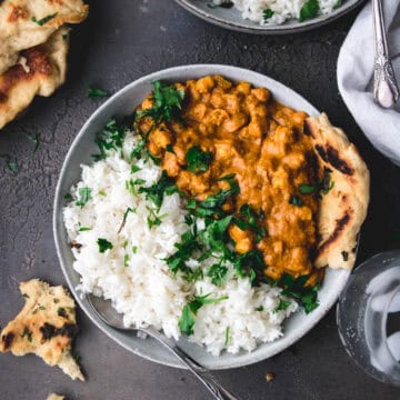 bowl of butter chickpeas next to ripped naan