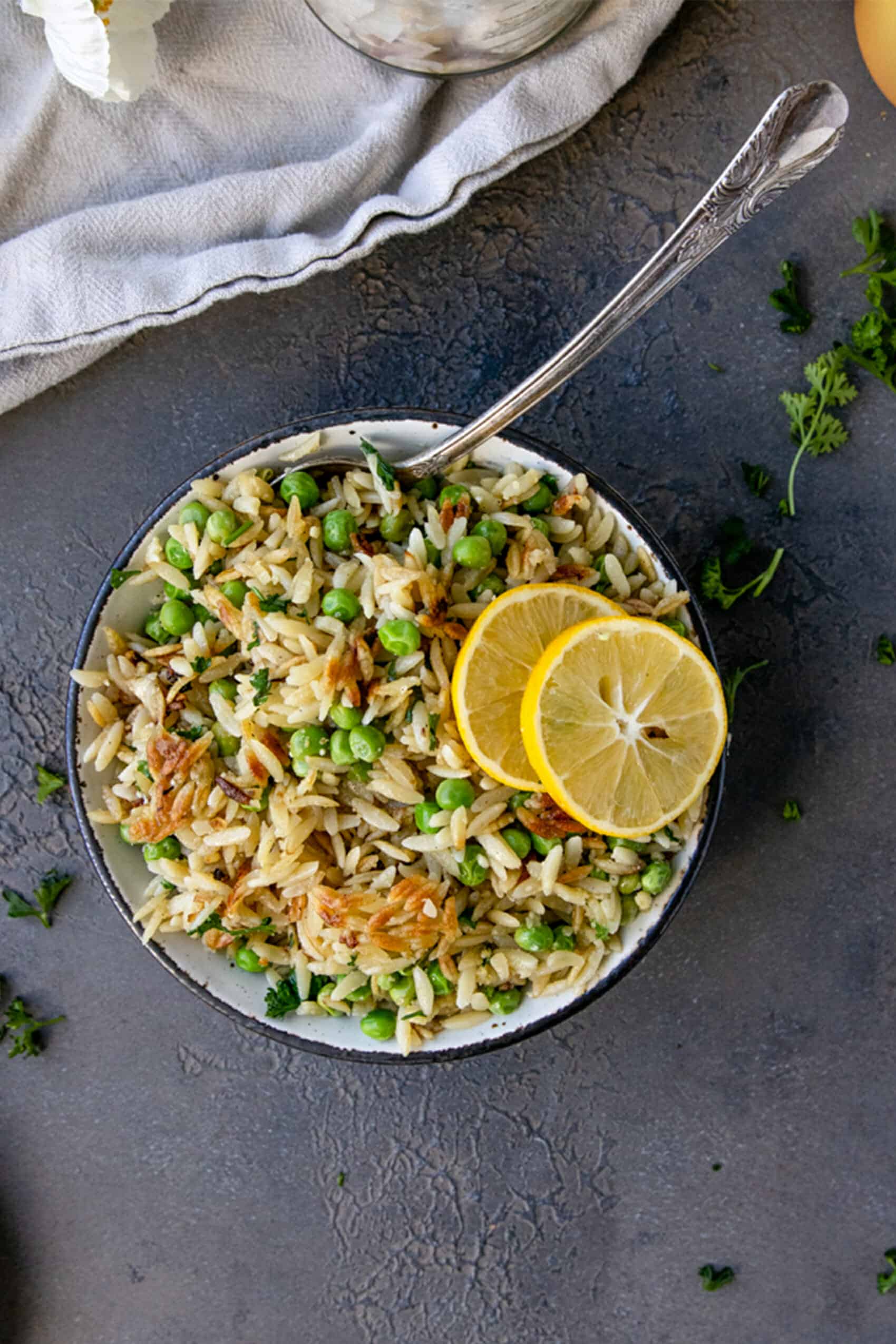 overhead shot of crispy orzo with peas and two lemon rounds