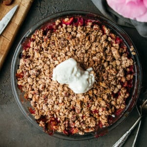 overhead shot of brown butter rhubarb crumble on a stone table with two scoops of vanilla ice cream