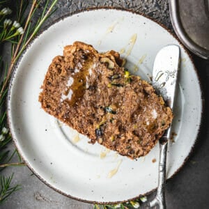 overhead shot of plant based zucchini bread on a white plate next to a silver knife