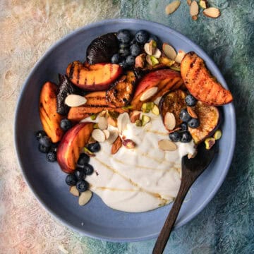 overhead shot of grilled peach yogurt bowls on next to chopped nuts