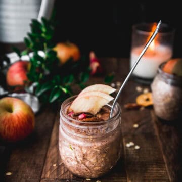 side view of apple pie overnight oats on a wooden table next to an apple