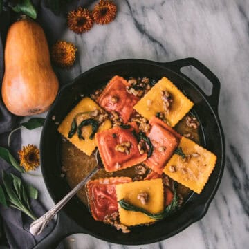 overehead shot of a cast iron skillet with butternut ravioli coated in sage brown butter