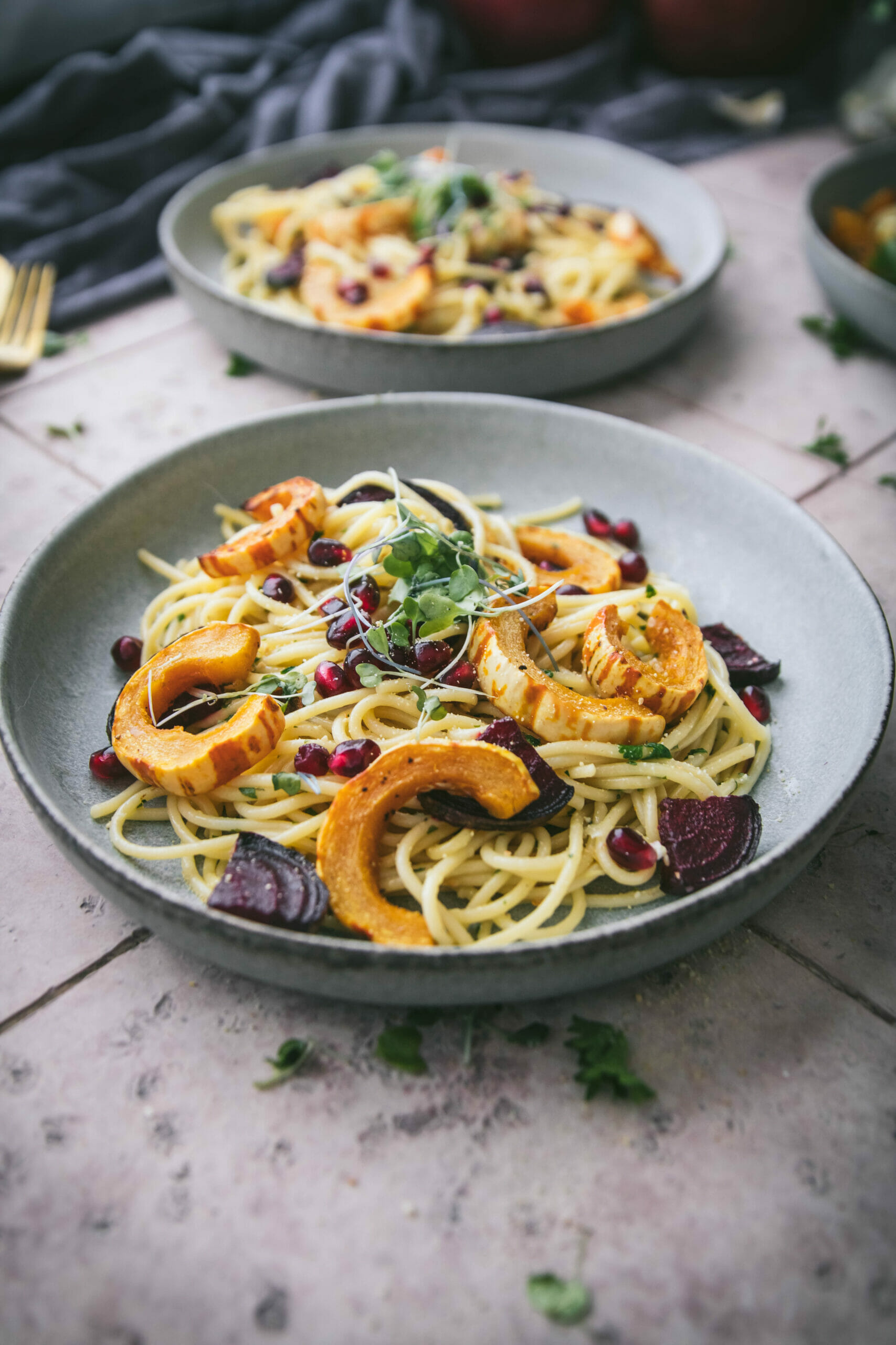 close up of a bowl of garlic spaghetti on a pink tile table