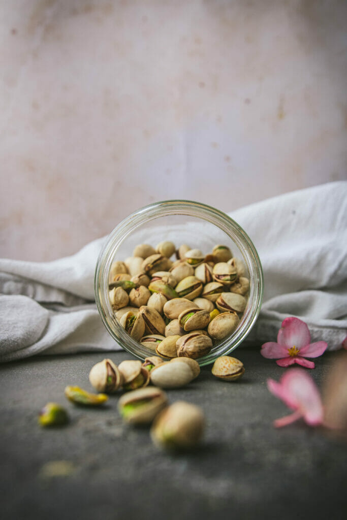 side view of an open glass jar of pistachios