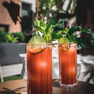 two carrot bloody mary cocktails on an outdoor table