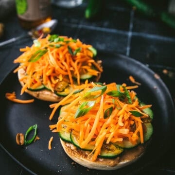 two pieces of Thai peanut bagel slices with carrots and cucumbers