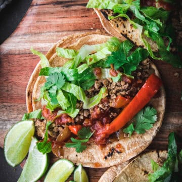 close up of walnut lentil taco meat in a tortilla with peppers and limes