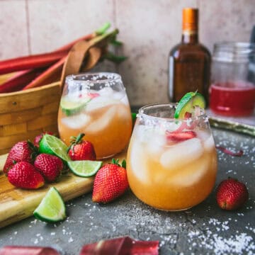 two strawberry rhubarb margaritas on a table next to fresh fruit