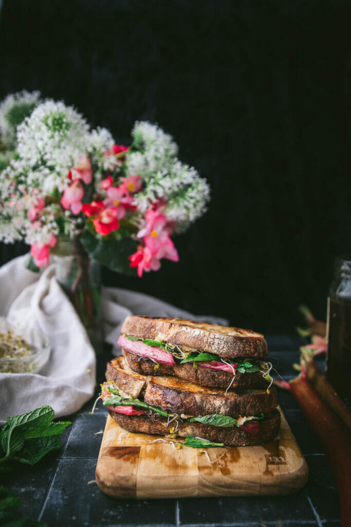 two stacked roasted rhubarb sandwiches next to a vase of flowers