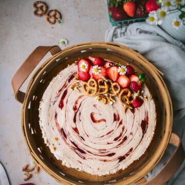 vegan strawberry pretzel cheesecake in a basket topped with pretzels and sliced berries