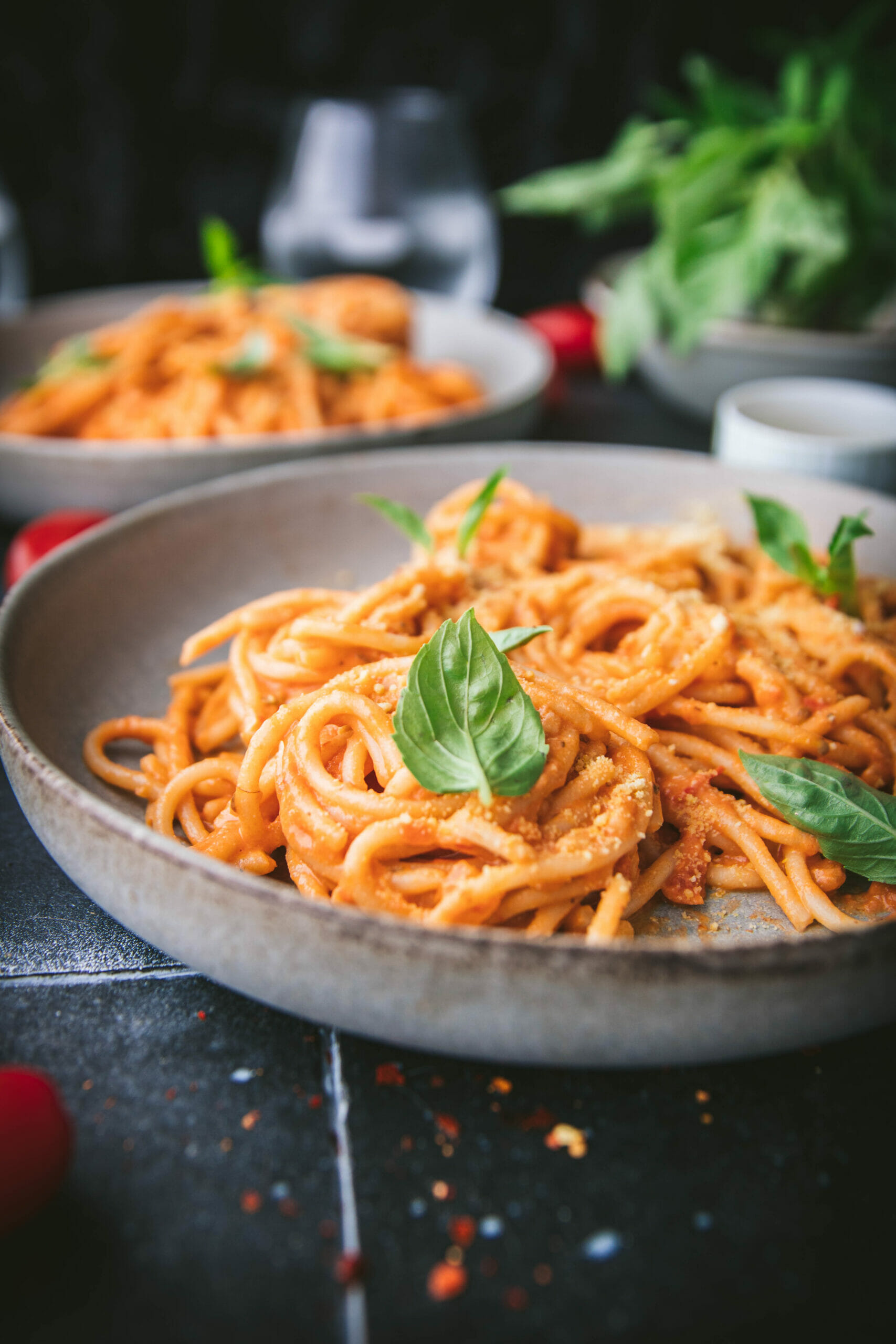 a close up shot of a basil leaf on a plate of vegan vodka sauce pasta