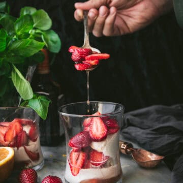 hand spooning strawberries into a grand marnier sundae