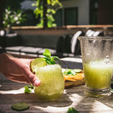 hand reaching for a frozen mojito slushie next to a pitcher