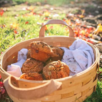 a side view of a basket of vegan pumpkin muffins next to fall leaves