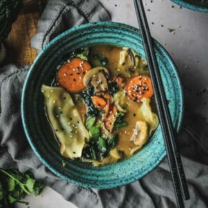 chopsticks and a bowl of miso dumpling soup with vegetables