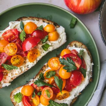 close up of whipped ricotta tomato toast on a plate