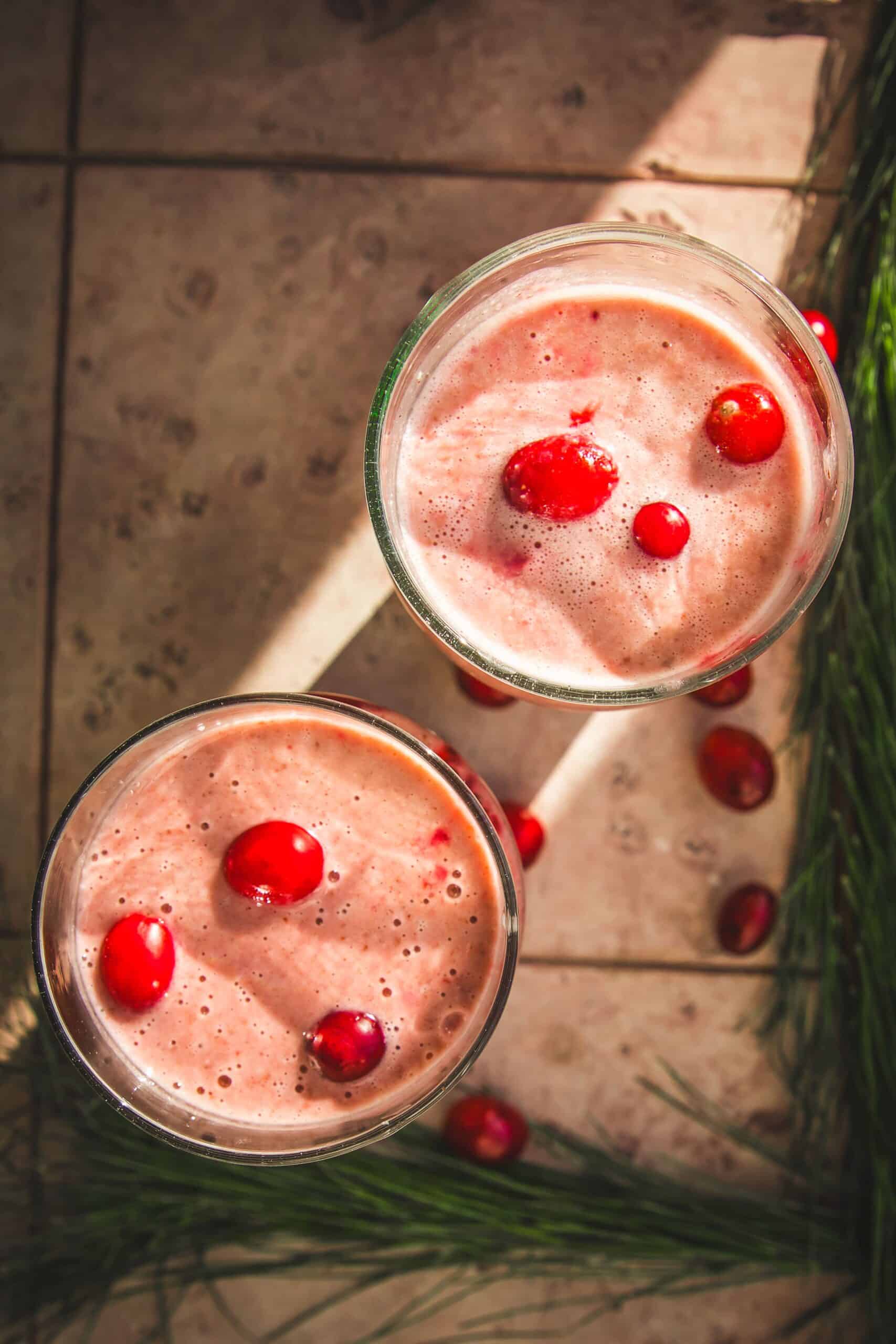 two cranberry orange smoothies with cranberry garnish.